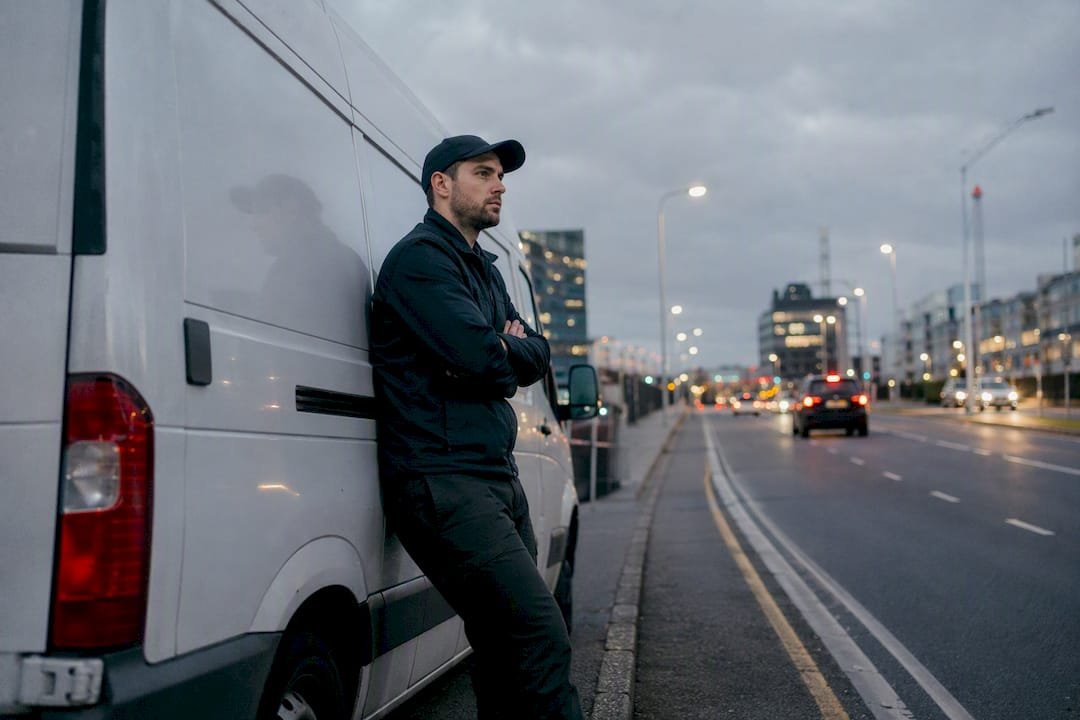 Delivery driver waiting beside van roadside